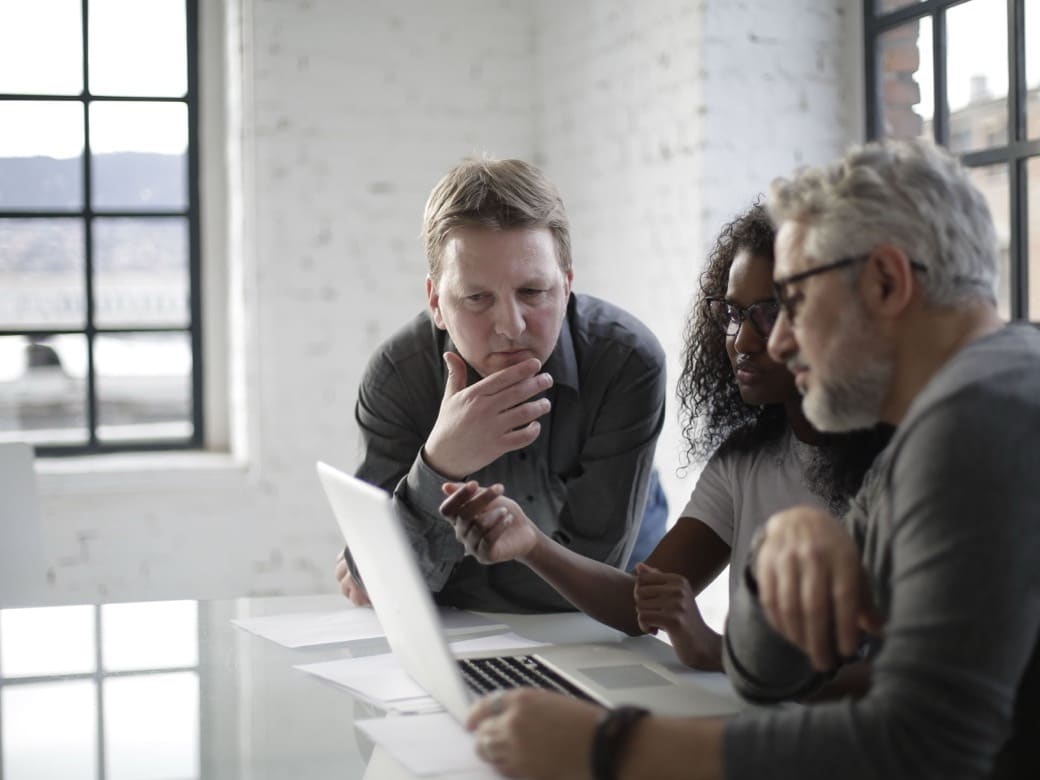 A team reviewing invoices and paperwork together at a laptop